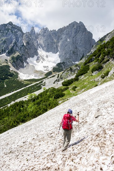 Female hiker crossing a snowfield on the Wilder-Kaiser-Steig hiking trail