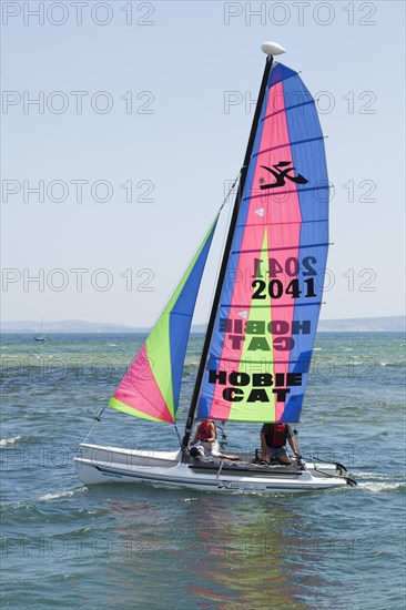 Two people sailing on a Hobie Cat catamaran