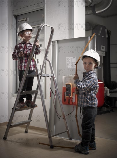 Twins with hard hats at play as construction workers