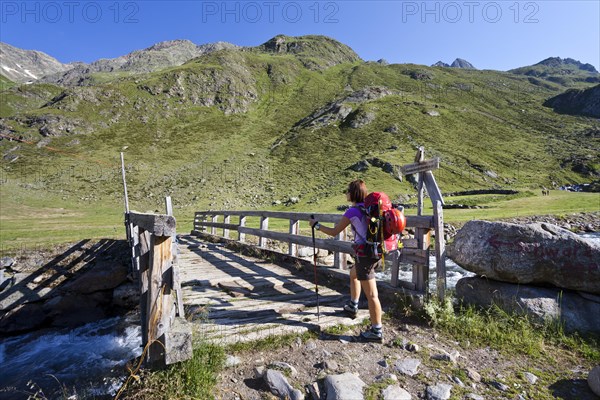 Female mountain climber at Timmelsalm alpine pasture crossing Timmlserbach stream