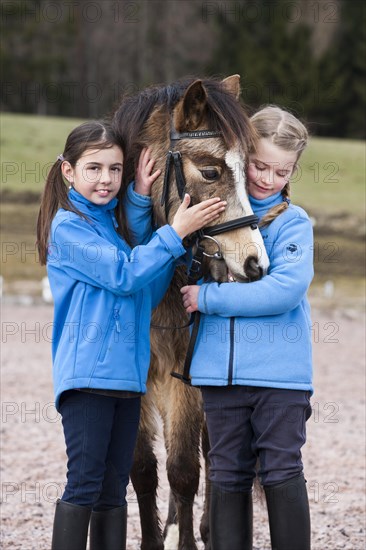 Two girls standing beside a pony