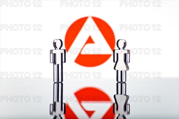 Two figures standing in front of the logo of the German employment agency