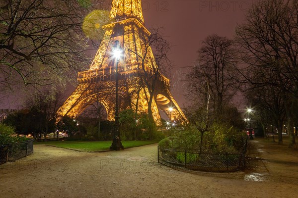 The base of the Eiffel Tower at night in the Parc du Champ de Mars