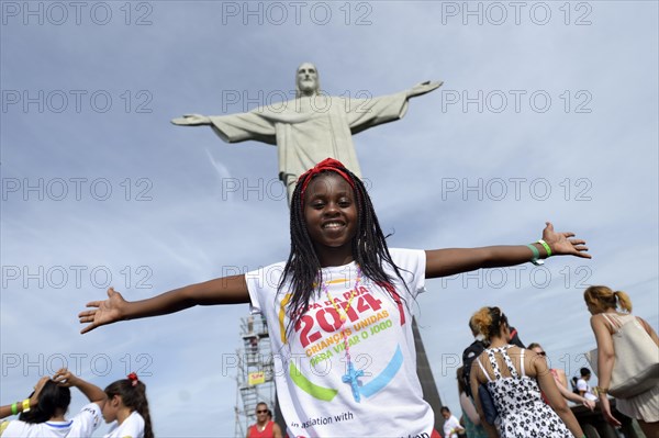 Young woman from Mozambique with her arms outstretched in front of the Christ the Redeemer statue