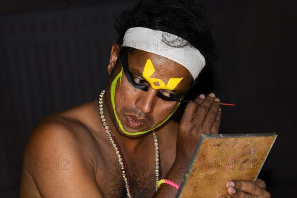 Kathakali dancer applying makeup in preparation for his performance