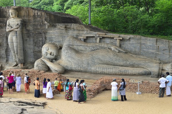 Tourists in front of a lying and a standing Buddha statue