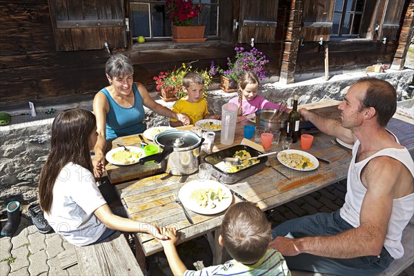 Family holding hands before lunching together in front of a mountain chalet