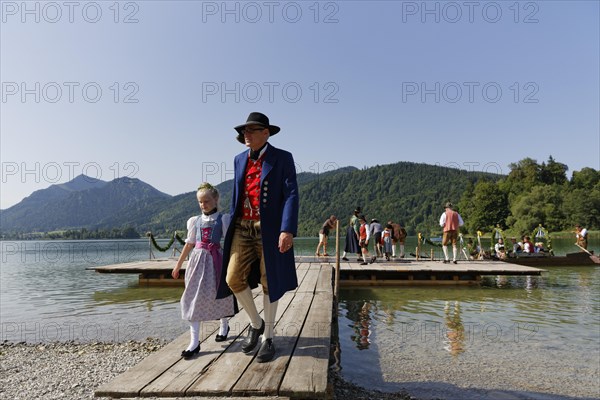 Locals wearing traditional costumes disembarking a boat at a jetty