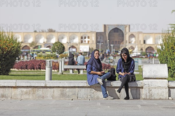 Young women using a mobile phone in front of the entrance to the Bazaar