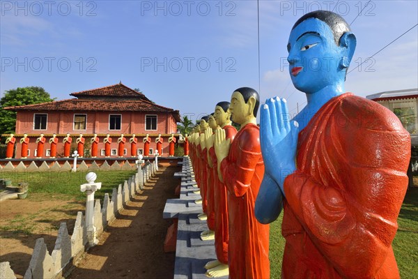 Figures of Buddhist monks in front of a monastery