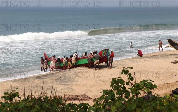 Fishermen pushing their boat out of the water onto the beach