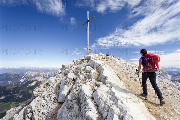 Mountaineer at the summit cross of Mt Heiligkreuzkofel of the Fanes Group in the Fanes-Sennes-Prags Nature Park