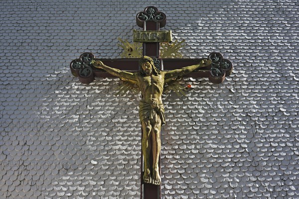 Carved wooden crucifix on the shingle facade of the parish church of St. Margaret