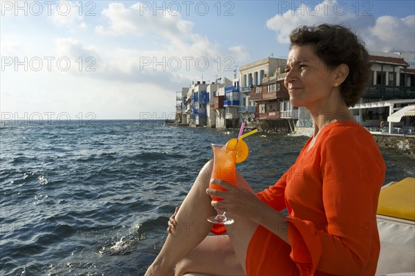 Woman enjoying a cocktail and a view over the sea