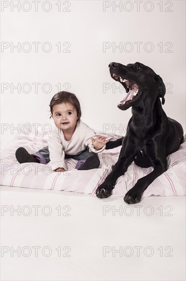 Big black mongrel lying next to a small child