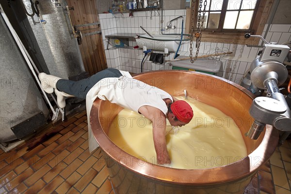 Dairyman spreading the cloth in a copper kettle to separate the whey from the curd and to skim off the cottage cheese