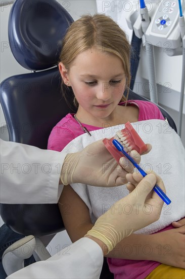 Dentist showing a girl the proper use of a toothbrush