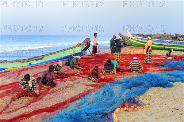 Fishermen repairing nets on the beach