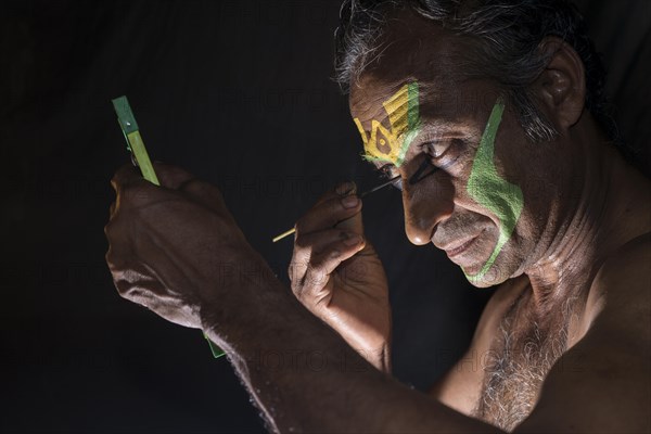 A Katakali artist is applying the make up of the character Arjun for the Kiritam play during a temple festival