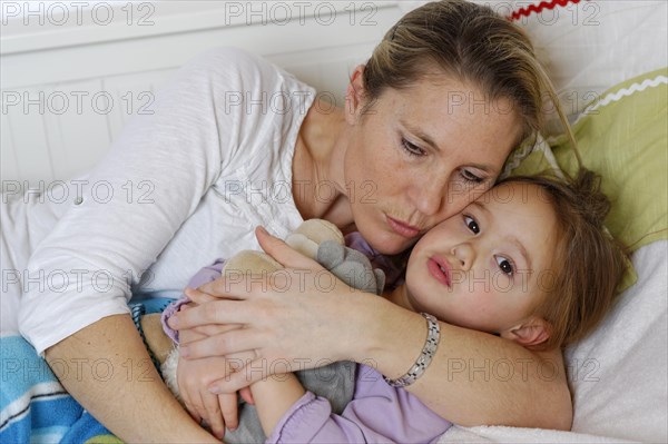 Mother and daughter cuddling in bed