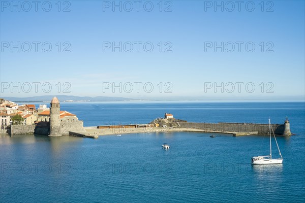 Sailboat in harbor near clocktower of Notre-Dame-des-Anges church