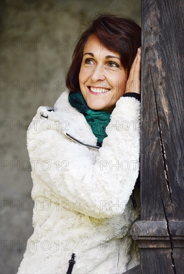 Smiling woman leaning on a wooden post