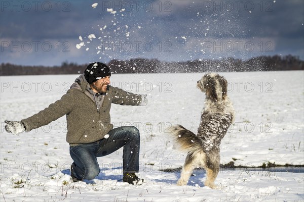 A man and his dog are playing in the snow on a field near Wustermark