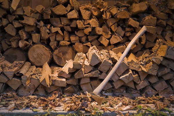 Axe and piles of stacked firewood in an outdoor shed