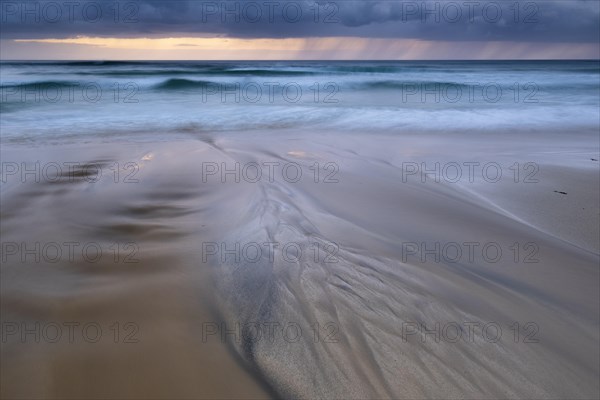 Water flows over bizarre structures on the sandy beach