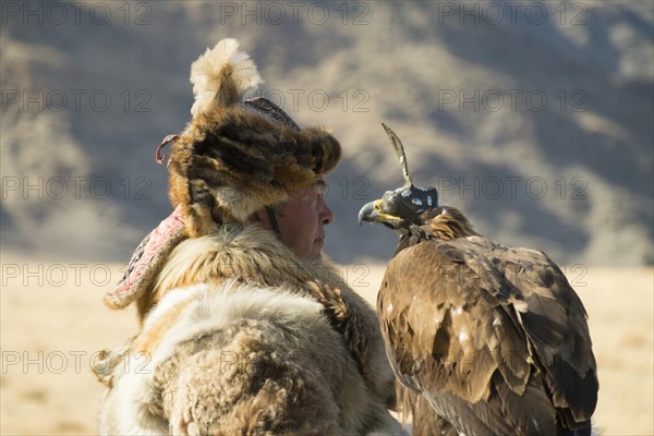 Kazakh eagle hunter wearing wolf fur holding an Festival in Sagsai