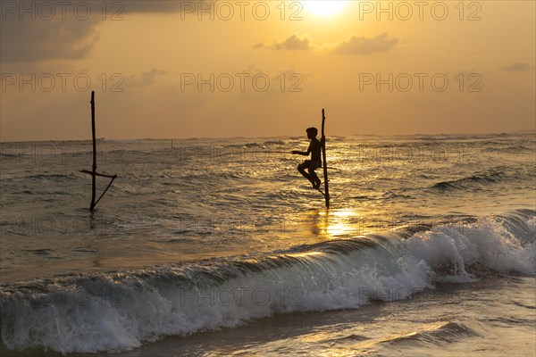 Stilt fisherman fishing in shallow water