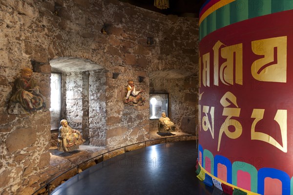 Room with a Tibetan prayer wheel and Buddha statues