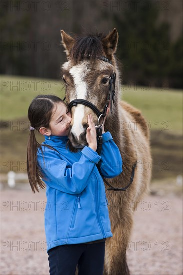 Girl cuddling with a pony