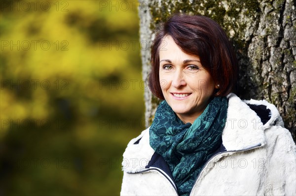 Smiling woman at a tree in autumn