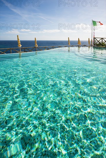 Swimming pool and the Mediterranean with the flag of Italy