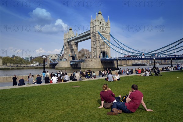 Tourists relaxing in Potters Fields Park in front of Tower Bridge