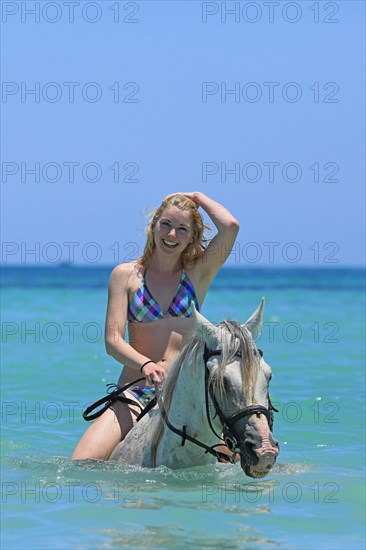 Woman wearing a bikini riding a Barb horse in the sea