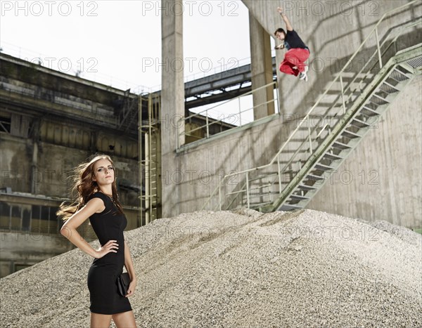 Young woman in black dress standing in front of a cement plant