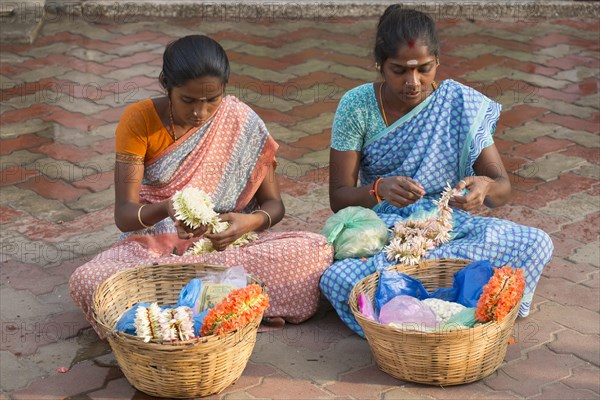 Two girls producing floral decorations to sell them later