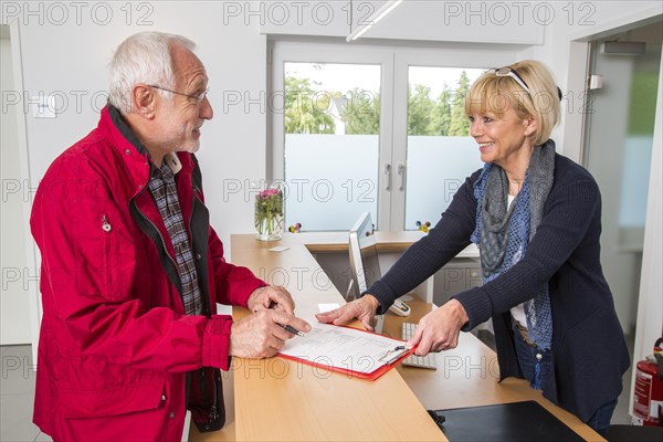 Patient filling in a form at the reception of a dental office