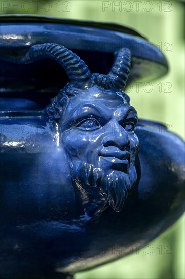 Human-animal head on an ornamental vessel made of glazed ceramic