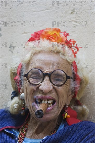 Old woman wearing coulorful clothes posing with a cigar