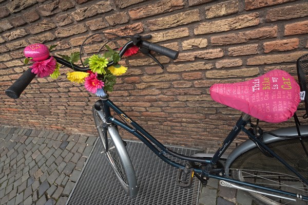 Bike decorated with flowers leaning against a wall