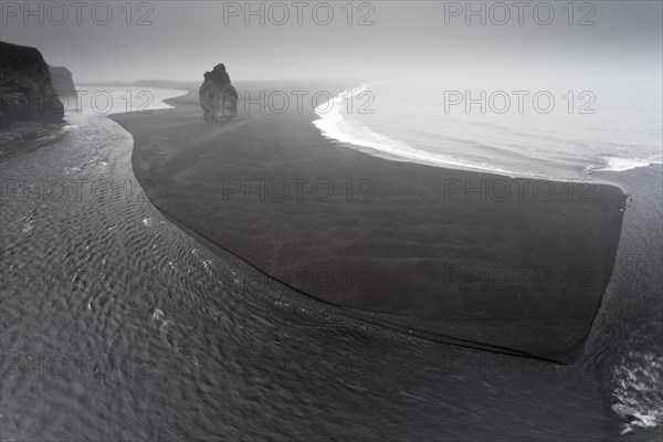 Black lava beach with a basalt rock