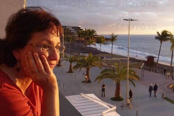 Woman looking from balcony over promenade of Puerto Naos