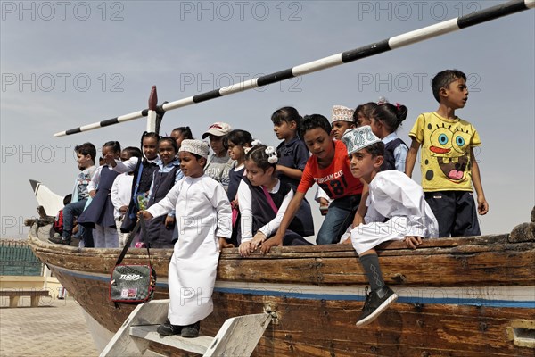 Group of Omani school children playing on an old dhow-ship