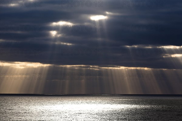 Sun rays shine through dark storm clouds