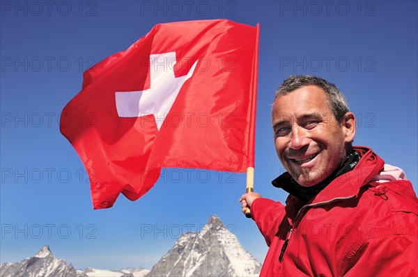 Tourist holding a Swiss flag over the Matterhorn