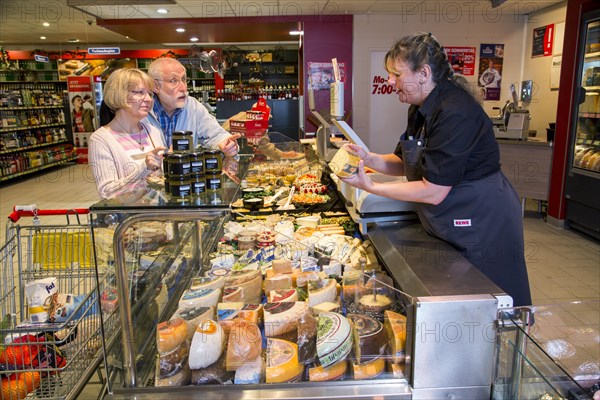 Shop assistant serving a senior couple at the cheese counter