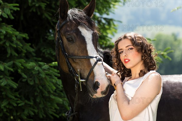 Young woman standing beside a horse